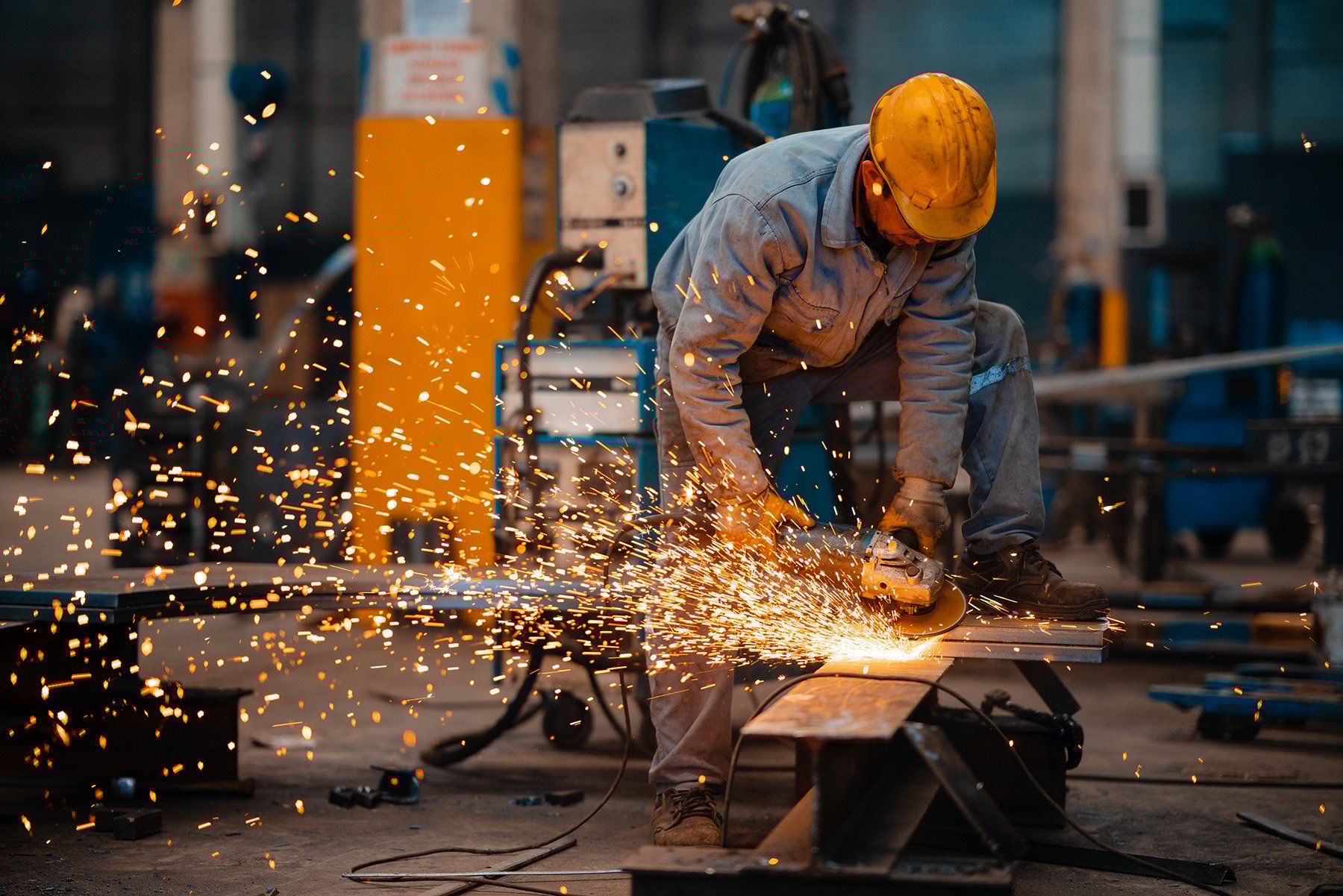 factory-worker-cutting-metal-with-grainder