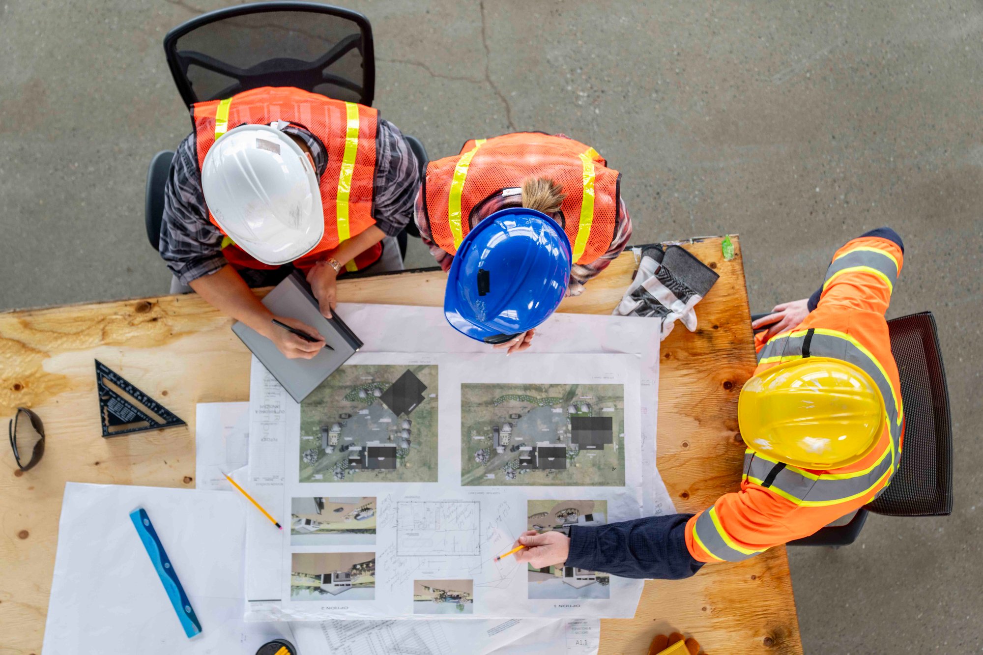 workers-standing-over-table-viewing-project-plans