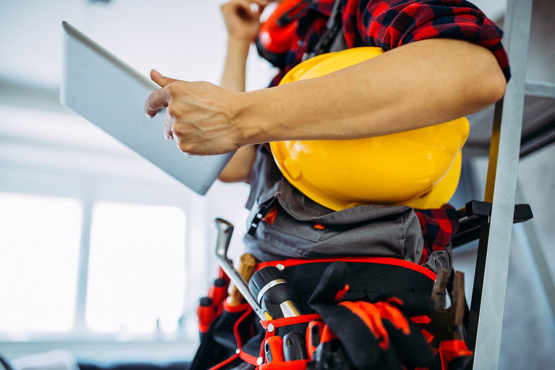 worker-viewing-digital-device-while-holding-safety-helmet worker-viewing-digital-device-while-holding-safety-helmet