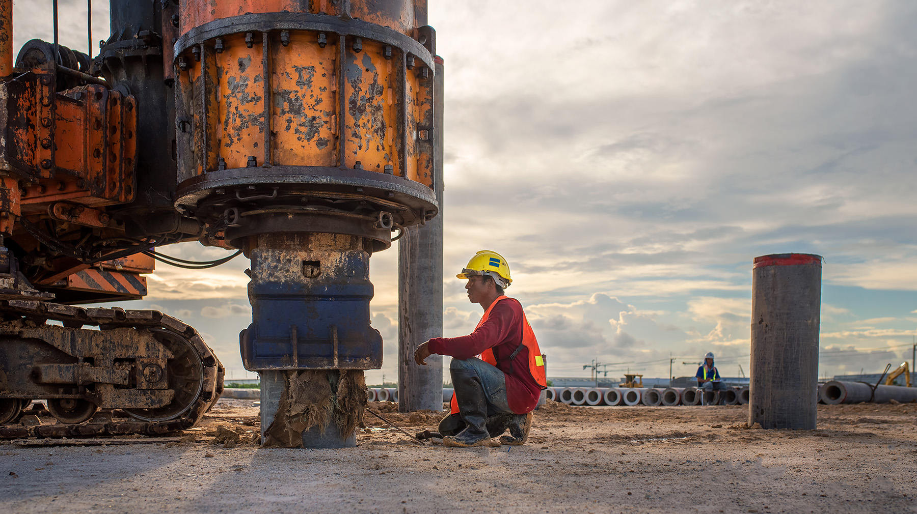 worker-kneeling-near-drilling-rig